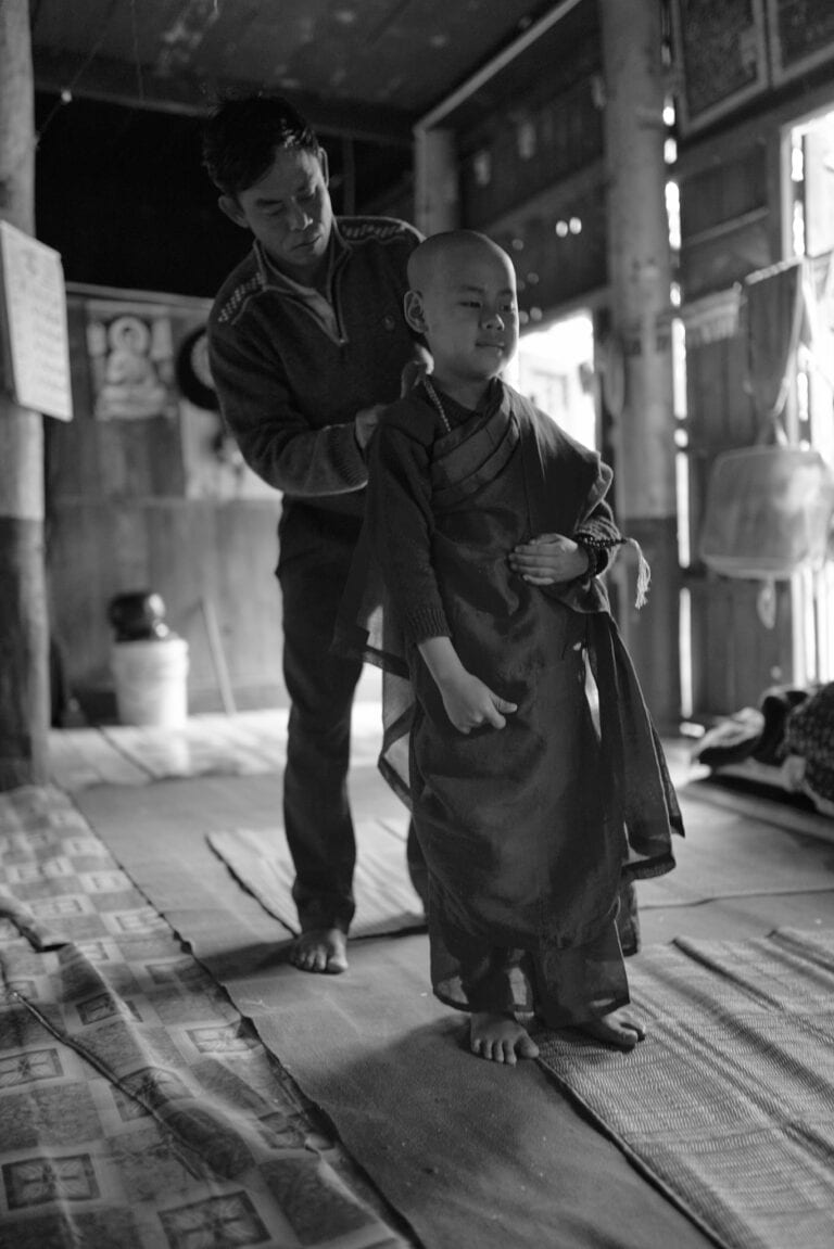 Apprentice monk getting help dressing